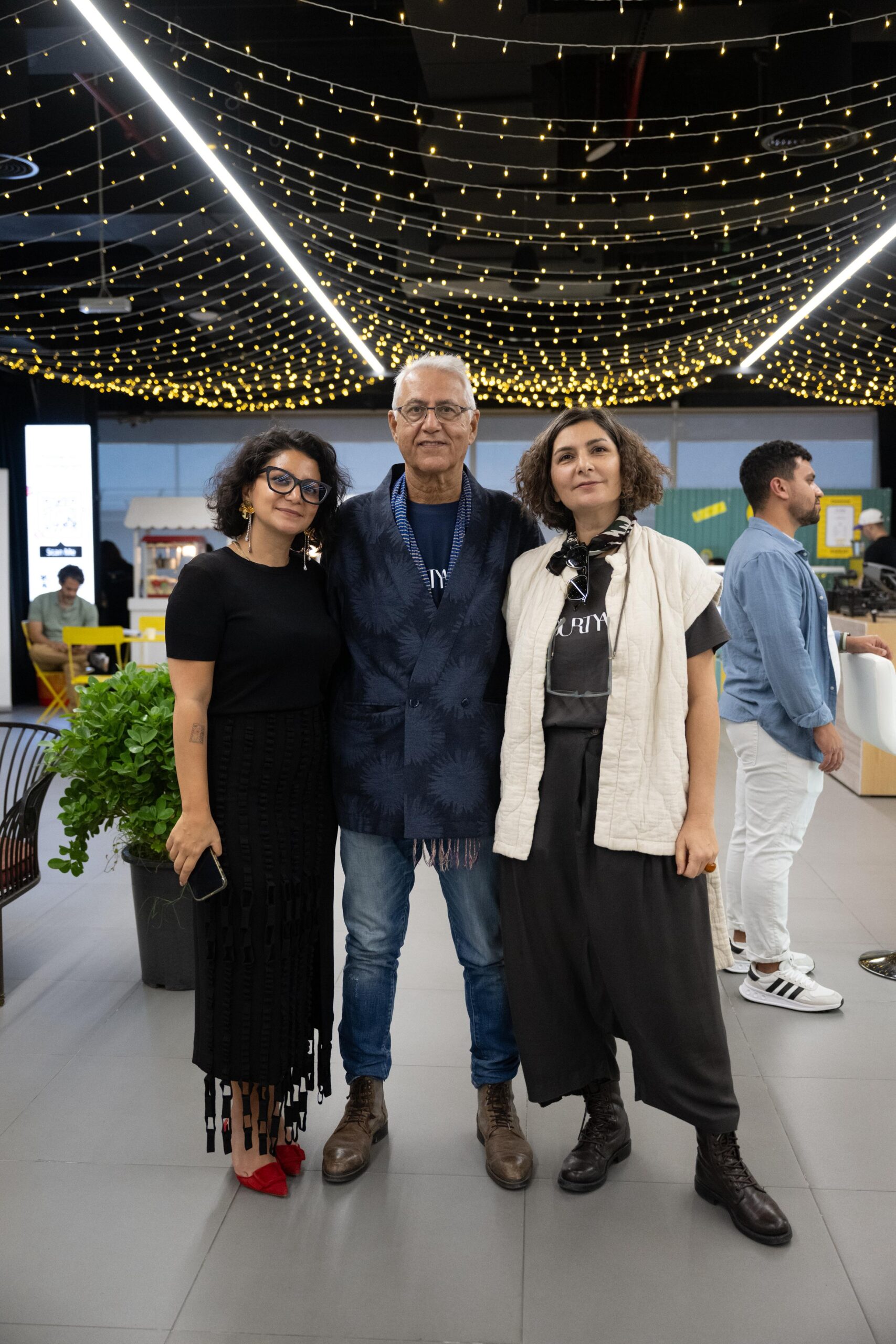 Parnian Farnam smiles for a picture with The Courtyard's designer and founder, Dariush Zandi alongside acclaimed artist Shaqayeq Arabi